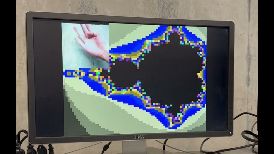 The fractal visualizer on a VGA monitor, with a hand gesture steering the zoom